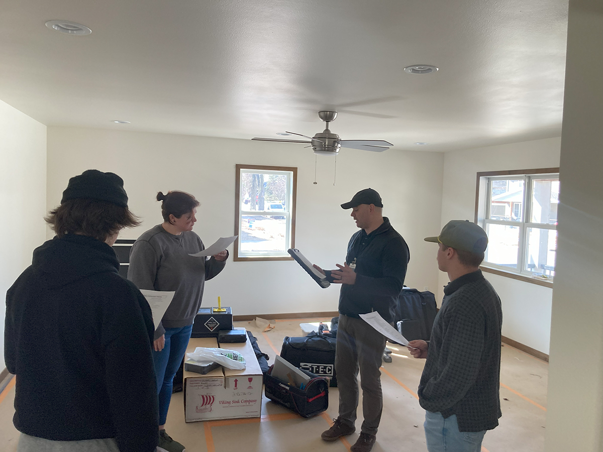 John addressing students within a finished house